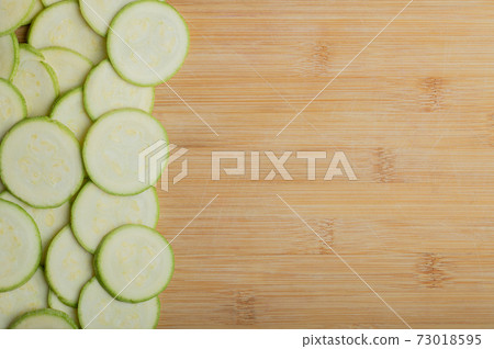 Close up photo of zucchini slices on brown background 73018595