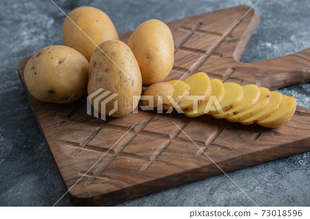 Close up photo of organic potatoes on wooden cutting board Close up photo of organic potatoes on wooden cutting board 73018596