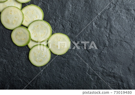 Close up Fresh zucchini slices on black background Close up Fresh zucchini slices on black background 73019480
