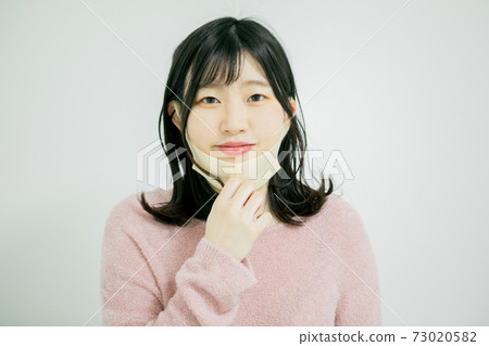 Young woman removing the mask Young woman removing the mask 73020582