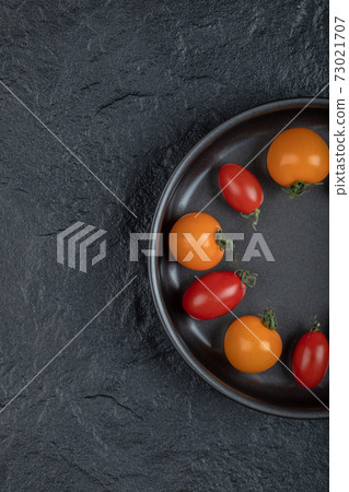 Half of Colorful cherry tomatoes in the pan on black background 73021707