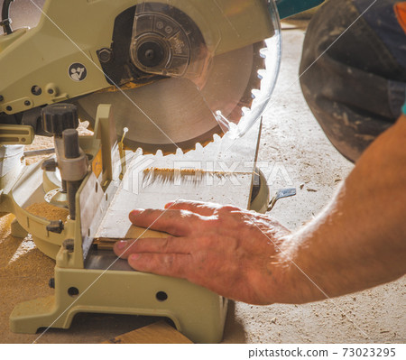 workman sawing a piece of wood workman sawing a piece of wood 73023295
