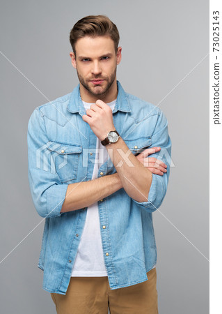 Portrait of young handsome caucasian man in jeans shirt over light background Portrait of young handsome caucasian man in jeans shirt over light background 73025143