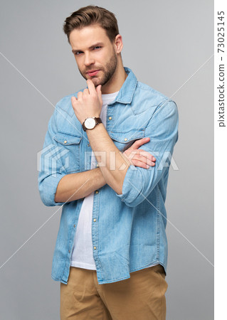 Portrait of young handsome caucasian man in jeans shirt over light background Portrait of young handsome caucasian man in jeans shirt over light background 73025145