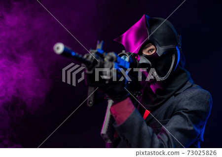 a man wearing a demon skull mask in a leather cloak with an airsoft gun 73025826