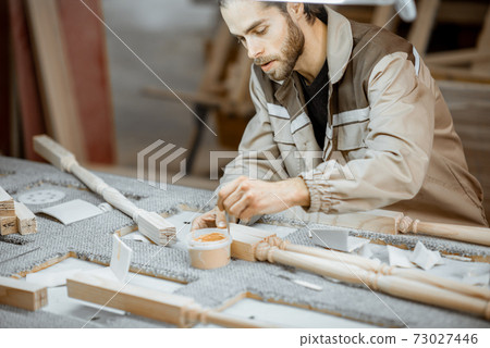 Manual worker finishing wooden products at the manufacturing 73027446