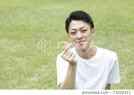 Finger heart pose young man face focus Finger heart pose young man face focus 73028311