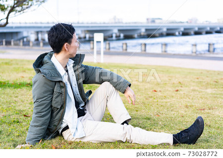 一個男人在公園的草地上放鬆 73028772