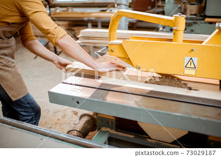 Carpenter sawing wooden planks 73029187