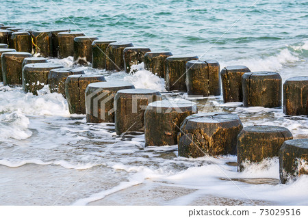 Groynes on shore of the Baltic Sea on a stormy day Groynes on shore of the Baltic Sea on a stormy day 73029516