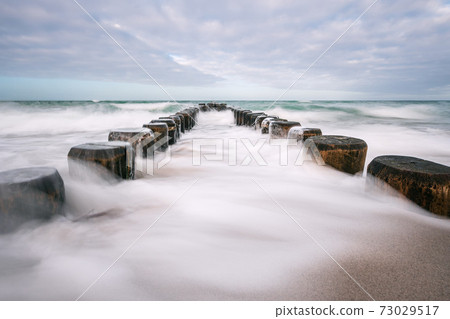 Groynes on shore of the Baltic Sea on a stormy day 73029517
