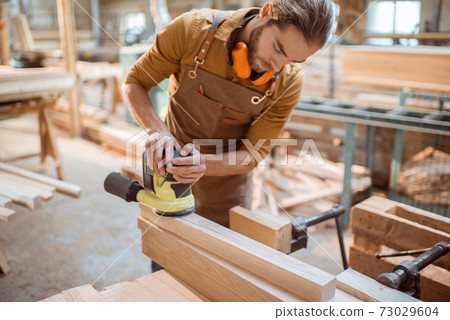 Carpenter grinding wooden bar 73029604