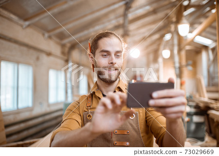 Carpenter using phone in the workshop Carpenter using phone in the workshop 73029669