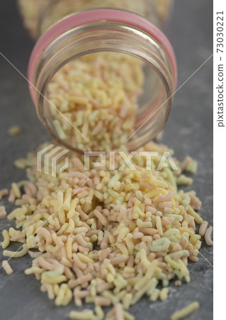 Sugar sprinkles dots in a bottle on dark background Sugar sprinkles dots in a bottle on dark background 73030221