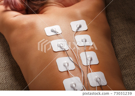 Muscle stimulator with electrodes, bacBack and shoulder massage with a muscle stimulator with attached electrodes along the spine. Muscle stimulator with electrodes, bacBack and shoulder massage with a muscle stimulator with attached electrodes along the spine. 73031239