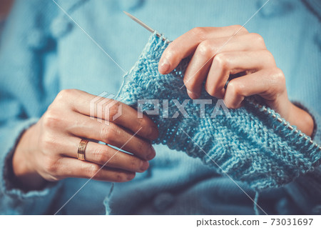 close up the woman's hands knitting a blue woolen sweater close up the woman's hands knitting a blue woolen sweater 73031697