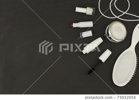 Cosmetics in white packaging on a dark background, lipstick, mascara, nail polish. Banner with space for text. 73032058