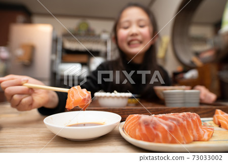 Girl eating salmon sashimi 73033002