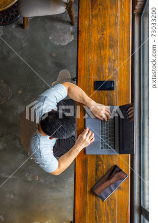 Top view of Asian freelancer using laptop on wooden table Top view of Asian freelancer using laptop on wooden table 73033200