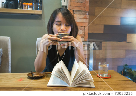Asian woman enjoy free time with book, coffee and music Asian woman enjoy free time with book, coffee and music 73033235