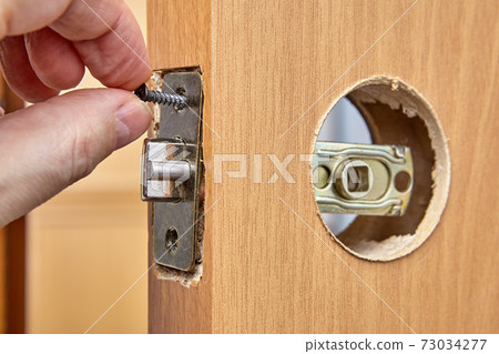 Locksmith secures the latch into the wood interior door with 2 screws. 73034277
