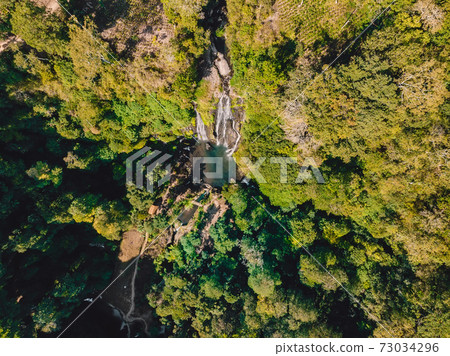 Waterfall with small lake in tropical jungle at Bali. Indonesia. Aerial drone view Waterfall with small lake in tropical jungle at Bali. Indonesia. Aerial drone view 73034296