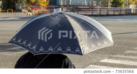 Lady with black umbrella on a sunny day. 73035568
