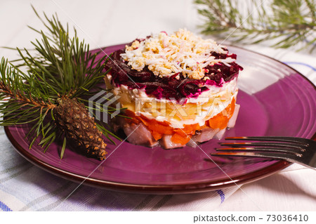 Traditional Russian herring under a fur coat in purple plate with parsley. Rustic style. Christmas russian salad. 73036410