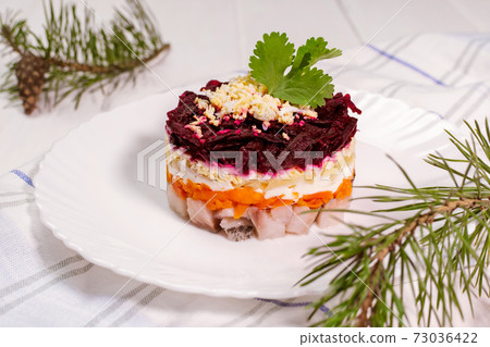 Traditional Russian herring under a fur coat in transparent plate with parsley. Rustic style. Christmas russian salad. Traditional Russian herring under a fur coat in transparent plate with parsley. Rustic style. Christmas russian salad. 73036422