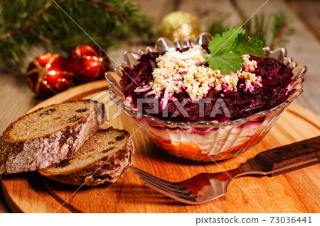 Traditional Russian herring under a fur coat in transparent plate with parsley. Rustic style. Christmas russian salad. Traditional Russian herring under a fur coat in transparent plate with parsley. Rustic style. Christmas russian salad. 73036441