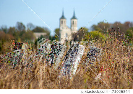 Graveyard plates in grass. Against the background of the church. Graveyard plates in grass. Against the background of the church. 73036844