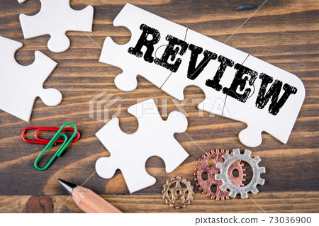 REVIEW. Business concept. White puzzle pieces on a wooden table REVIEW. Business concept. White puzzle pieces on a wooden table 73036900