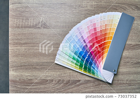 Color wheel palette for choosing paint tone. Various colors on wooden table background with copy space. Interior designer tool. 73037352