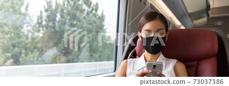 Train passenger Asian business woman using mobile phone during travel commute wearing face mask for corona virus pandemic. Panoramic banner of businesspeople commuting 73037386