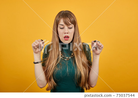 Beautiful awesome young points with index fingers down. Shocked amazed 73037544