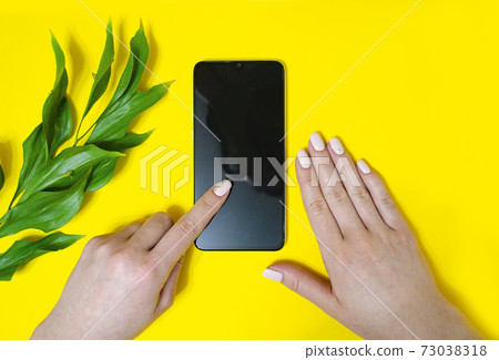 The girl holds the phone in her hand. Flipping through The girl holds the phone in her hand. Flipping through 73038318