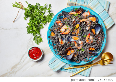 Black pasta with seafood on a marble background 73038709