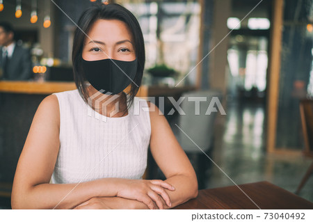 Asian mature business woman wearing protective face mask for coronavirus prevention in indoors public space as work office, restaurant, cafe Asian mature business woman wearing protective face mask for coronavirus prevention in indoors public space as work office, restaurant, cafe 73040492