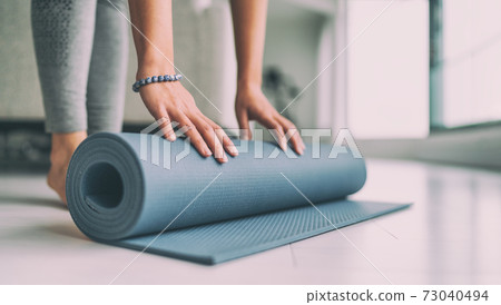 Yoga at home active lifestyle woman rolling exercise mat in living room for morning meditation yoga banner background Yoga at home active lifestyle woman rolling exercise mat in living room for morning meditation yoga banner background 73040494