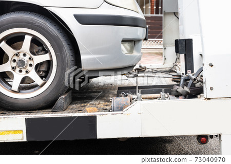 Broken down car towed onto flatbed tow truck 73040970