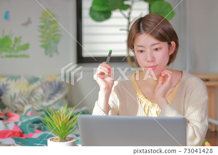 Telework_A woman with a smiling expression holding a pen Telework_A woman with a smiling expression holding a pen 73041428
