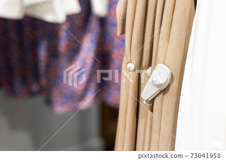 Close-up of RFID theft security tag attached onto apparels in clothing shop 73041958