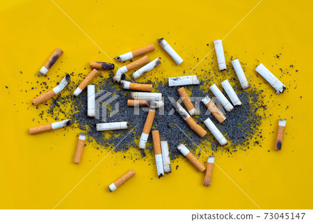 Smoked cigarettes on yellow background. Smoked cigarettes on yellow background. 73045147