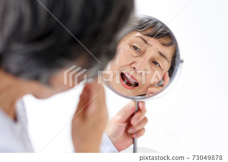 Senior woman watching a mirror Senior woman watching a mirror 73049878