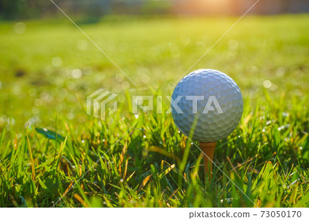 Golf ball on tee in the evening golf course with sunshine background. Golf ball on the green with warm tone and sunset. Golf ball on tee in the evening golf course with sunshine background. Golf ball on the green with warm tone and sunset. 73050170