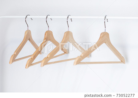 Many wooden hangers on a rod, isolated on white wall background. Store concept, sale, design, empty hanger Many wooden hangers on a rod, isolated on white wall background. Store concept, sale, design, empty hanger 73052277