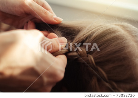 Mom is combing her daughter's hair. Taking care of baby's hair. The concept of a happy childhood and a good attitude towards children. Happy family Mom is combing her daughter's hair. Taking care of baby's hair. The concept of a happy childhood and a good attitude towards children. Happy family 73052720