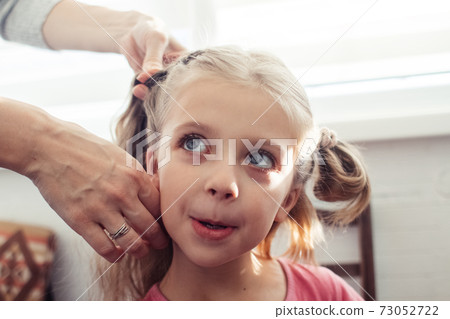 Mom is combing her daughter's hair. Taking care of baby's hair. The concept of a happy childhood and a good attitude towards children. Happy family 73052722