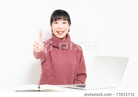 A woman who makes a like gesture while using a laptop A woman who makes a like gesture while using a laptop 73052732