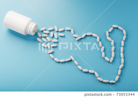 Biceps from white dragees with vitamins and minerals, Protein from a jar on a blue background. Biceps from white dragees with vitamins and minerals, Protein from a jar on a blue background. 73053344
